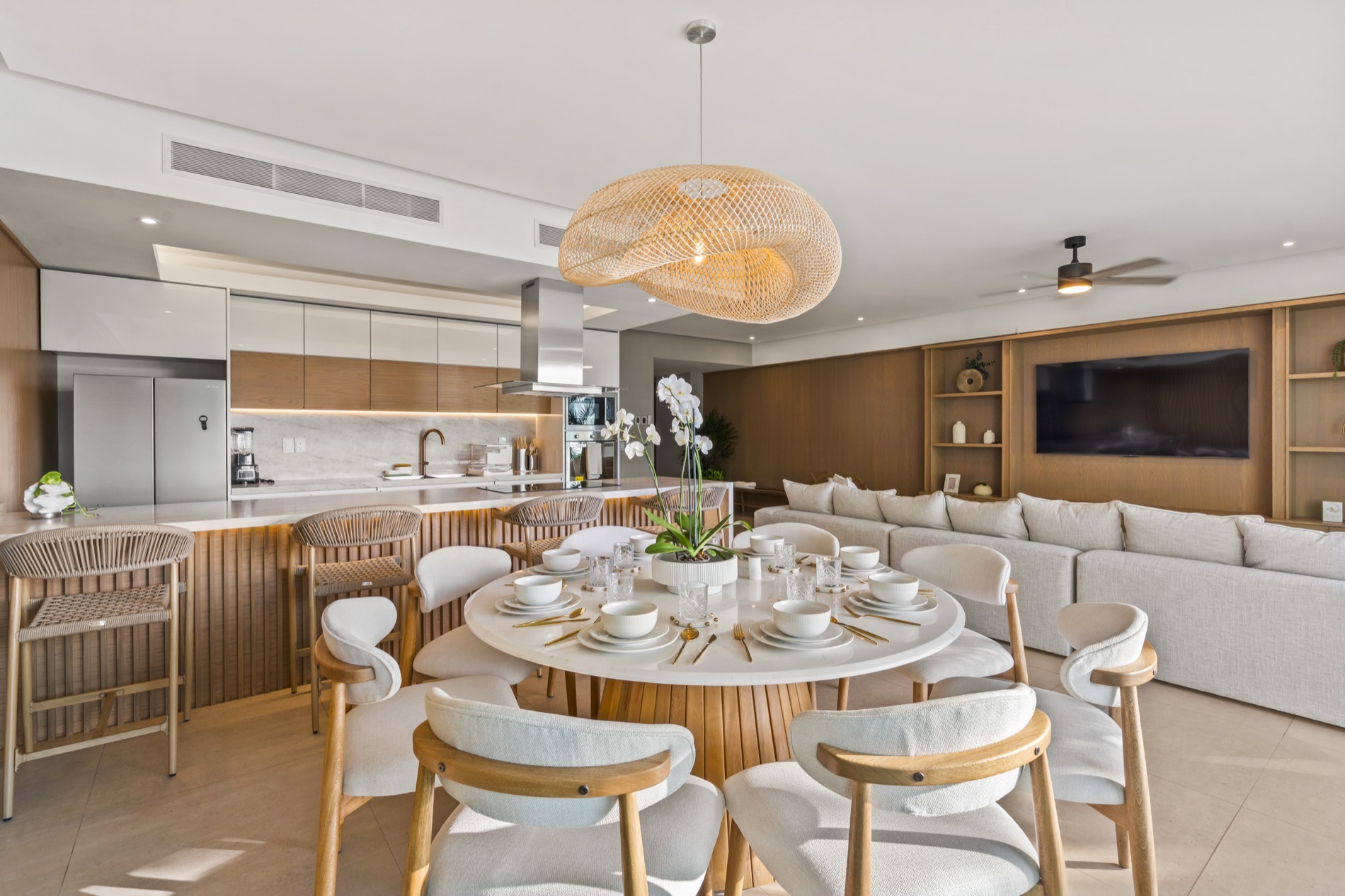 Comedor del departamento con lámparas de fibra natural y la cocina al fondo