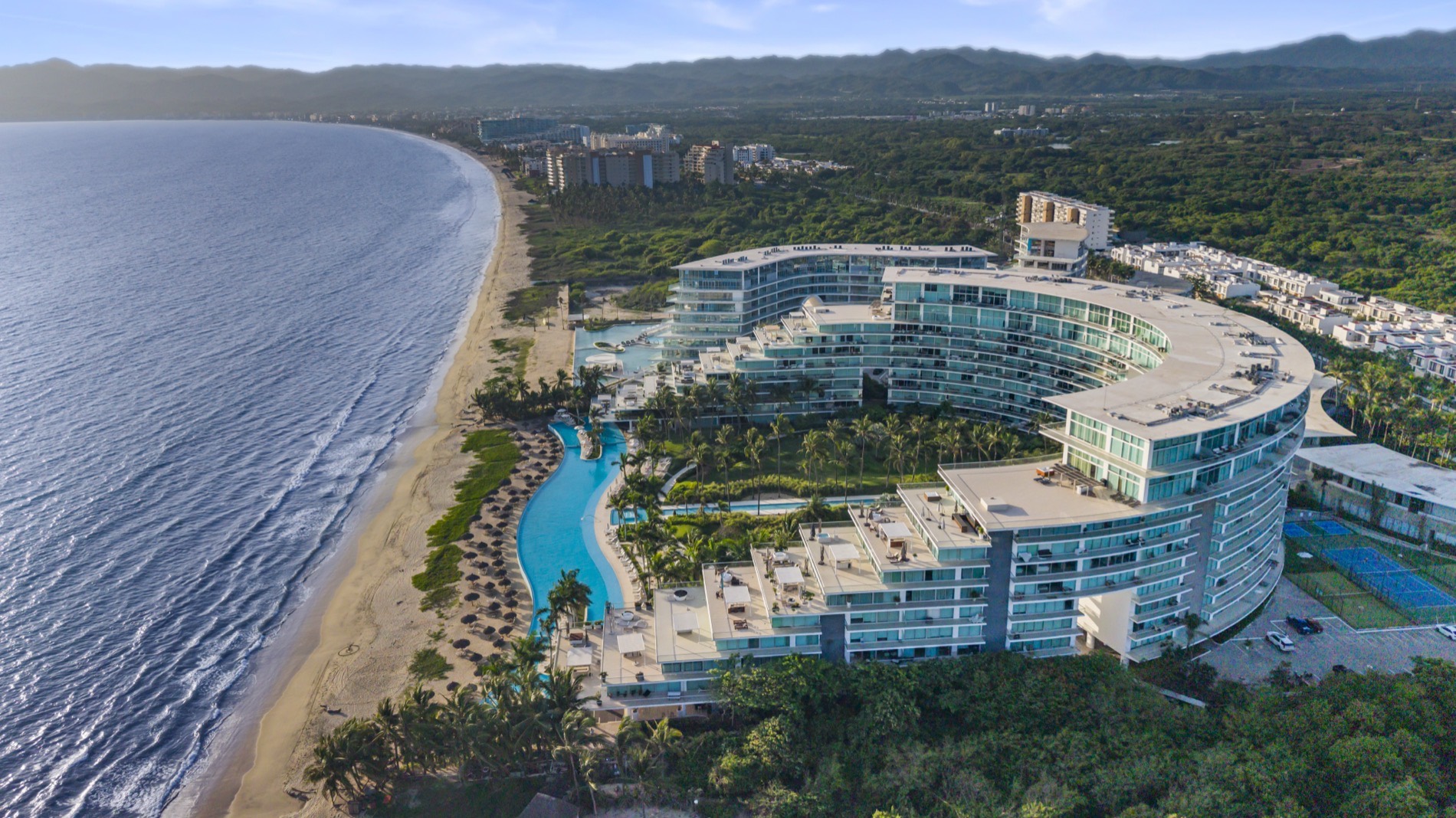 El resort curvo visto desde el aire, con sus albercas a lo largo de la playa